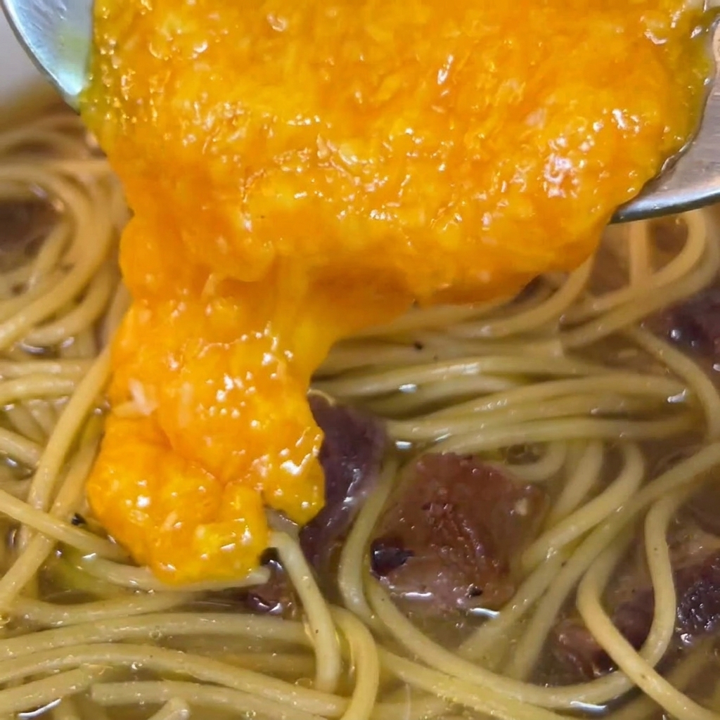 Il composto duovo versato sopra la pasta in padella.