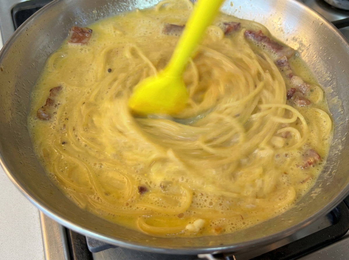 Pasta mescolata con il sugo cremoso in padella.