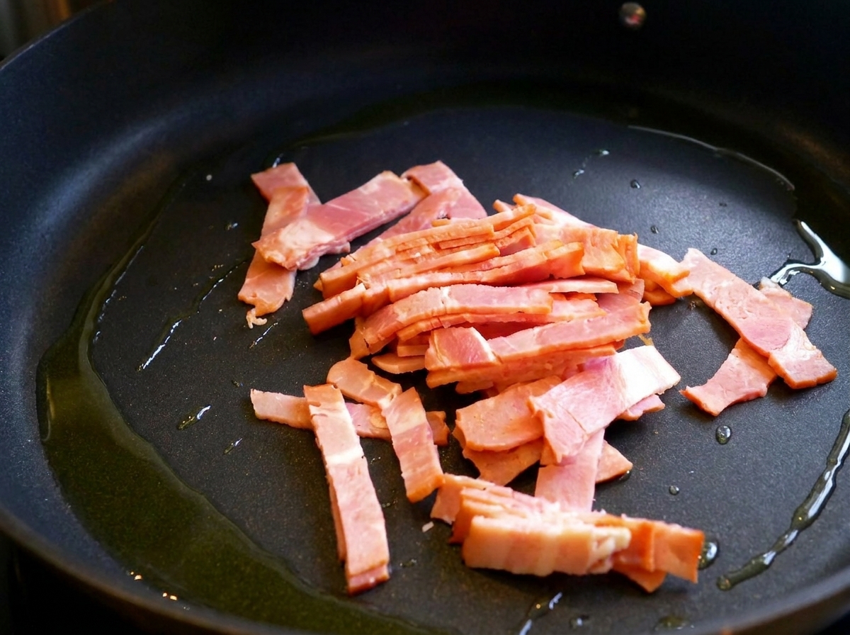 Pancetta che frigge in una padella con un filo dolio.
