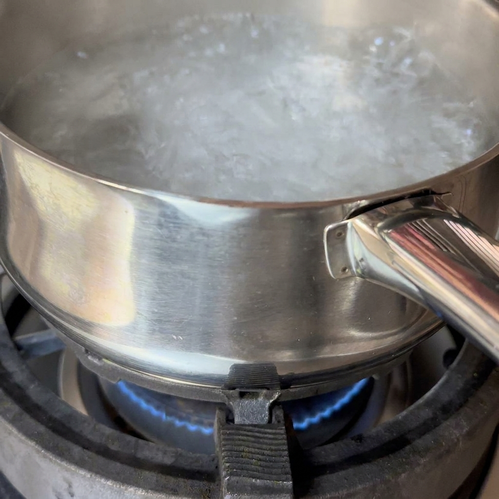 Spaghetti immersi in una pentola di acqua bollente mentre vengono mescolati con le bacchette.