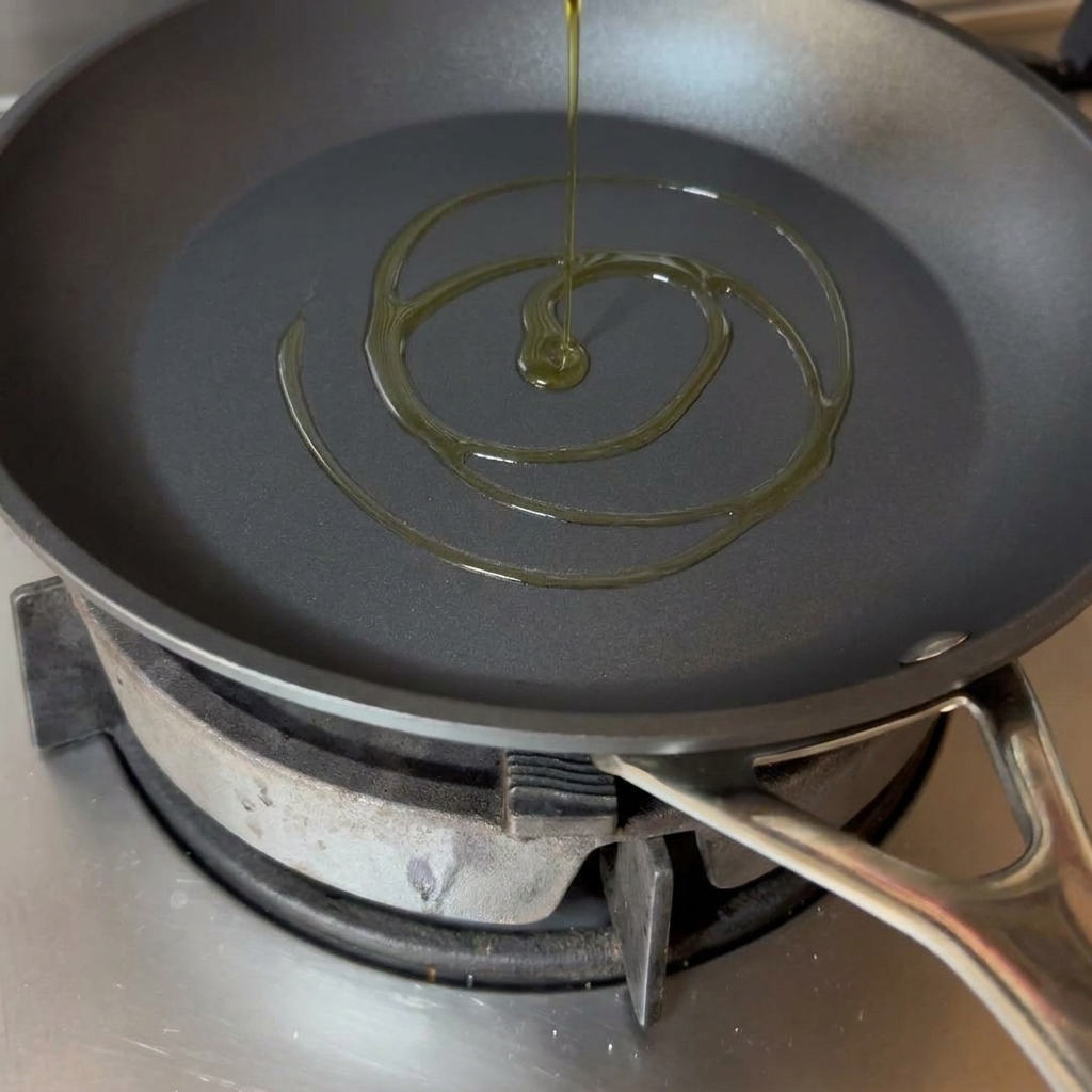 Un giro dolio doliva dorato sul fondo di una padella nera.