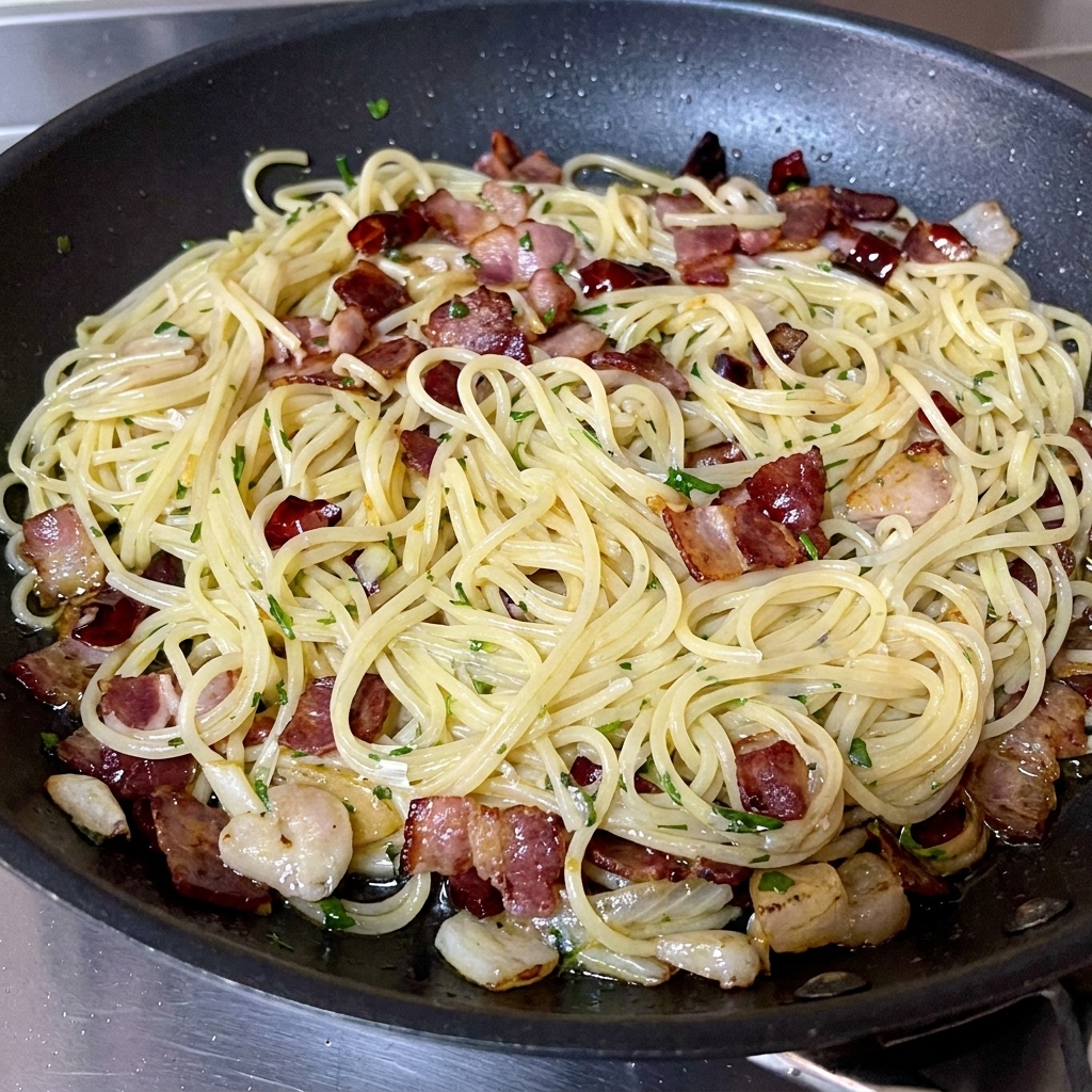Prezzemolo fresco tritato cosparso su una padella finita di spaghetti e pancetta.
