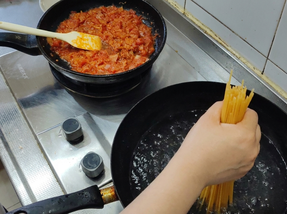 Una manciata di spaghetti secchi immersi in una pentola di acqua bollente.