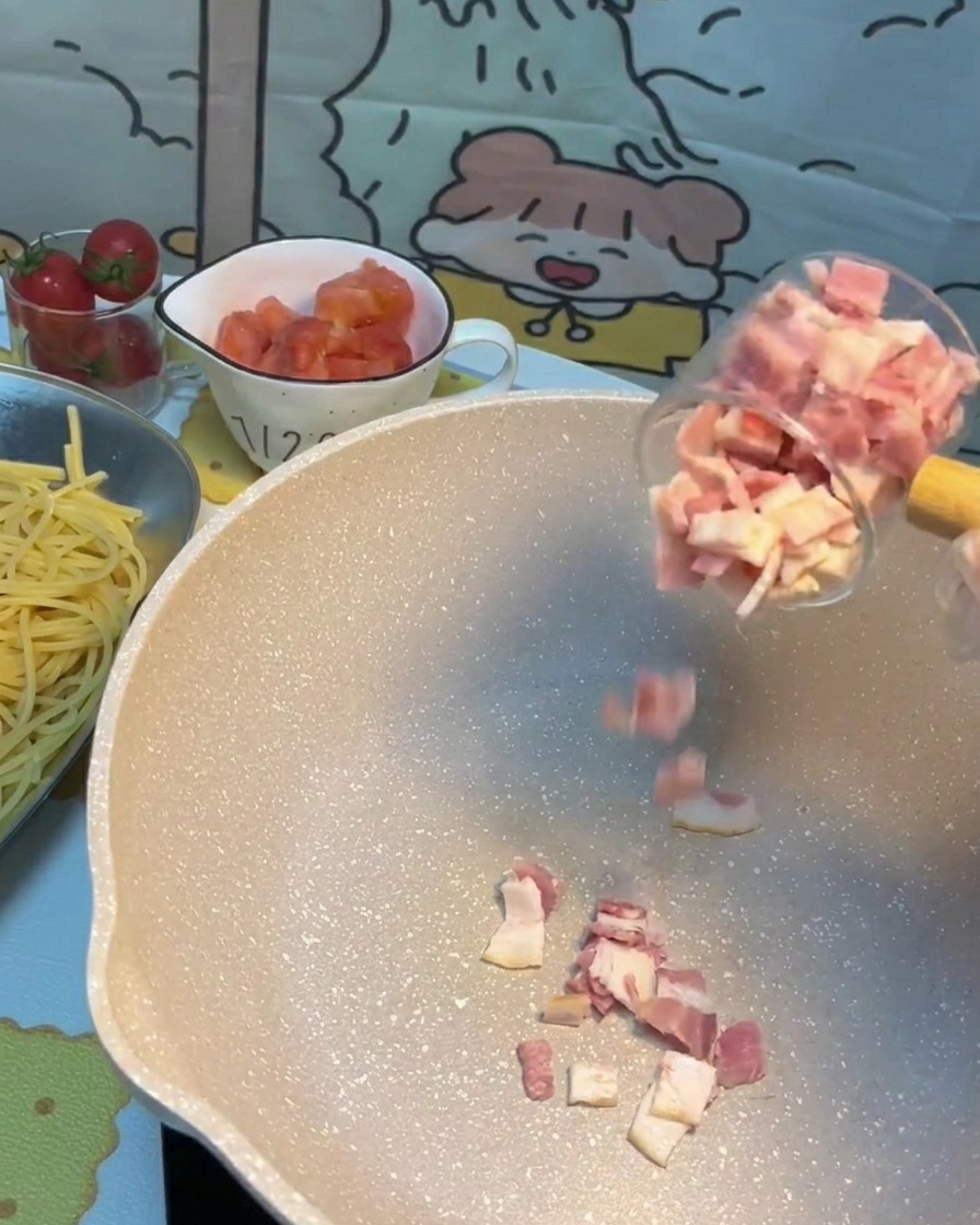 Pezzetti di pancetta che sfrigolano e dorano in una padella calda.