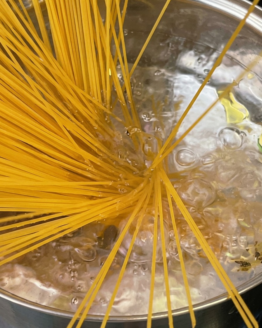 Pasta al dente sollevata da una pentola con un forchettone, con vapore che sale.