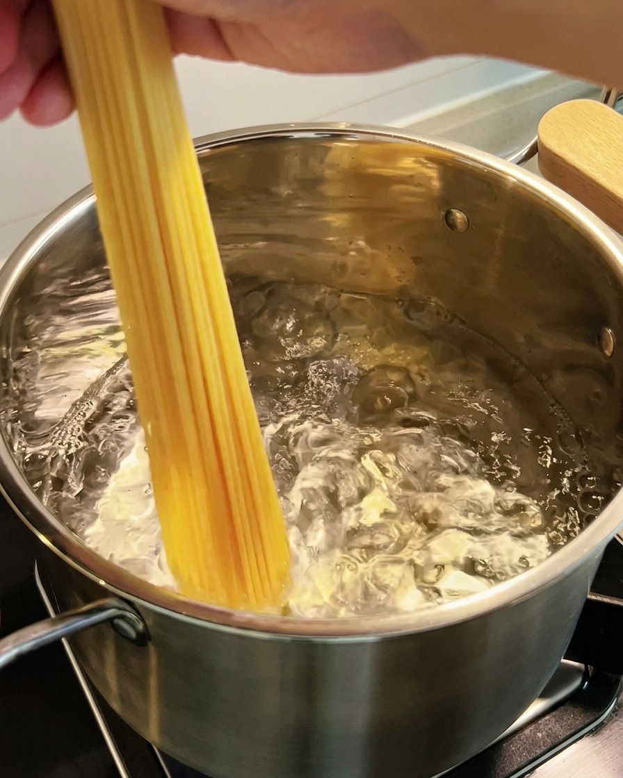 Spaghetti immersi in una pentola di acqua bollente.