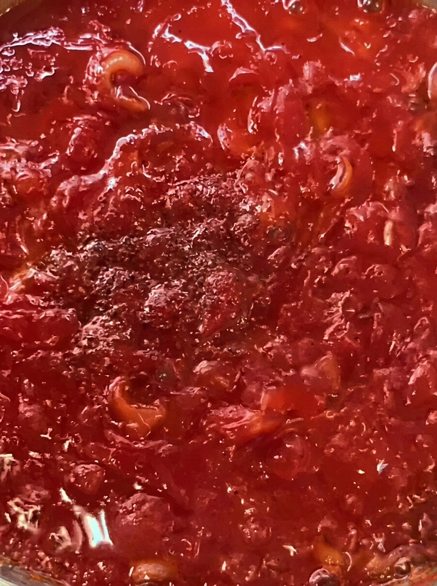Pancetta e pomodorini che cuociono in padella con olio.