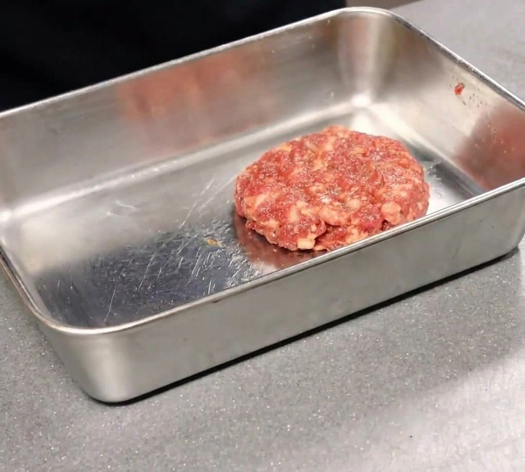 Pizza appena sfornata tagliata a fette con una rotella su un tagliere di legno.