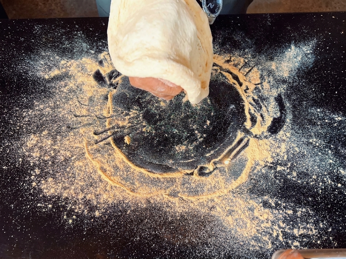Mani che fanno ruotare e allargano in aria limpasto per la pizza.