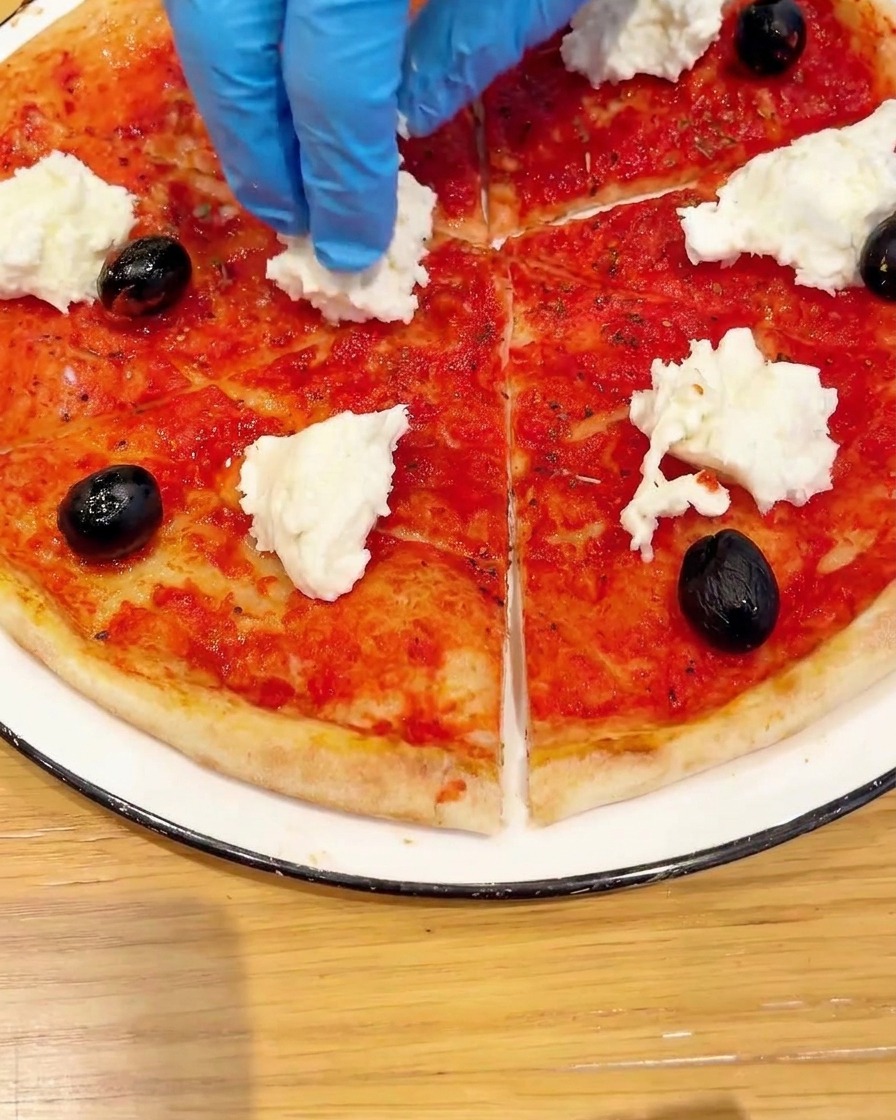 Vista dallalto di una base per pizza guarnita con pomodorini freschi e foglie di basilico verde.