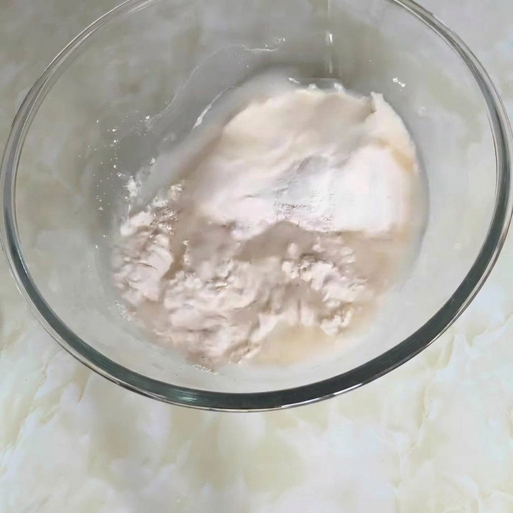 Primo piano di una ciotola con farina, acqua e altri ingredienti mescolati per formare limpasto.