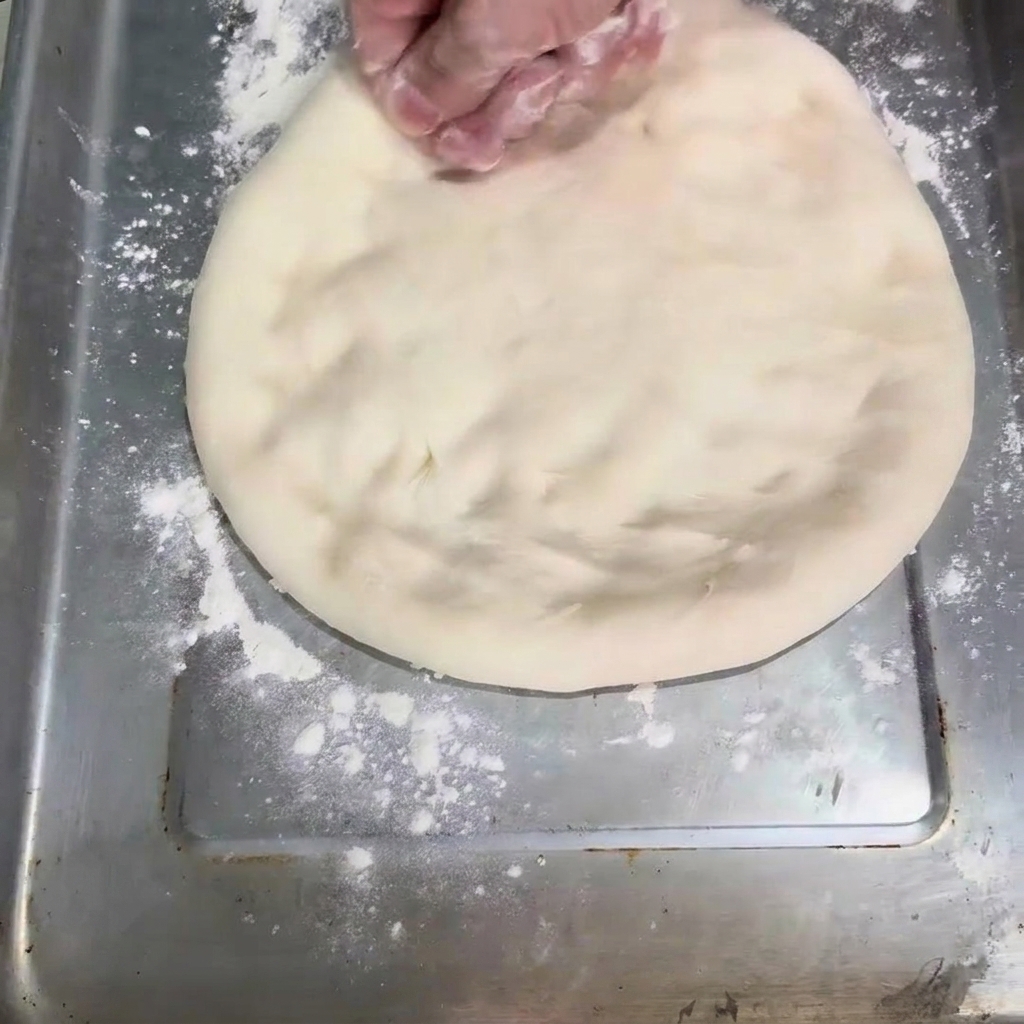Limpasto appiattito a forma di disco su una teglia da forno.