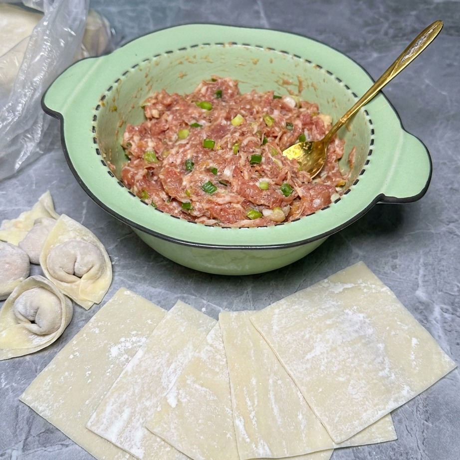Una pallina di ripieno di carne cruda posizionata al centro di un quadrato di pasta per wonton.