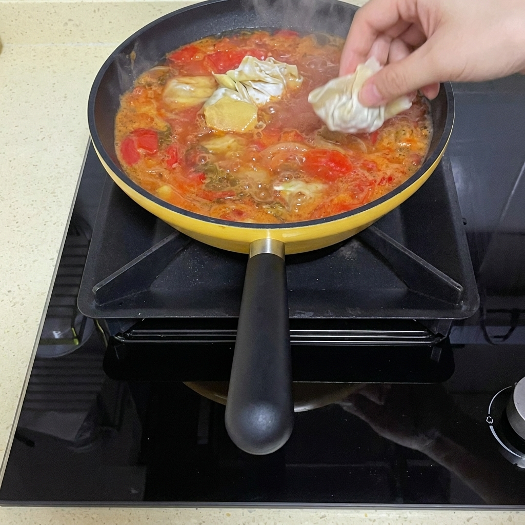 Wonton crudi piegati immersi nel brodo di pomodoro in ebollizione.