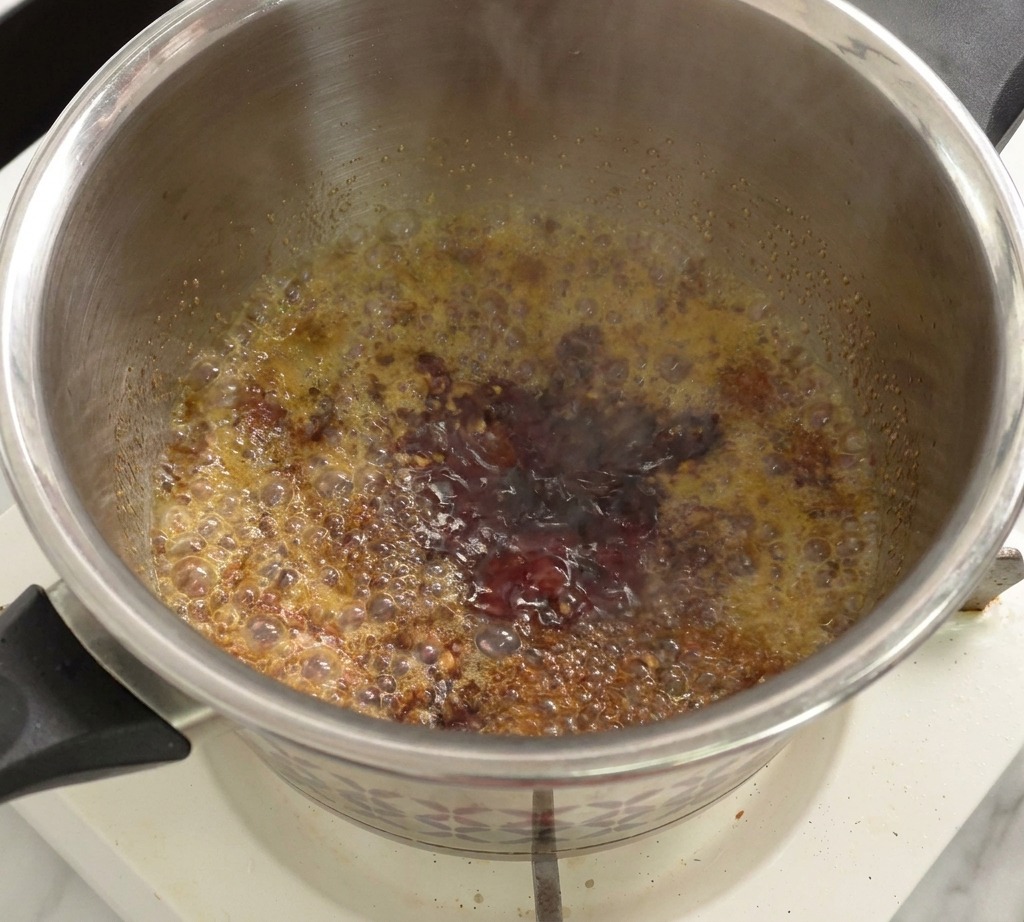 Un mix di salsa di pomodoro e aceto che sobbolle in una pentola sul fornello.