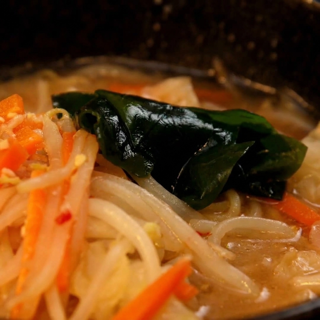 I noodle ramen cotti vengono trasferiti dalla pentola alla ciotola con la base di miso.