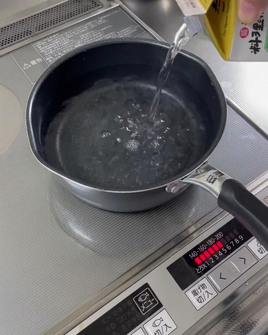 Acqua versata in un pentolino sui fornelli.