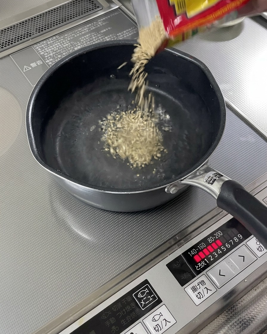 Semi di sesamo tostati che cadono in una pentola di liquido in ebollizione.