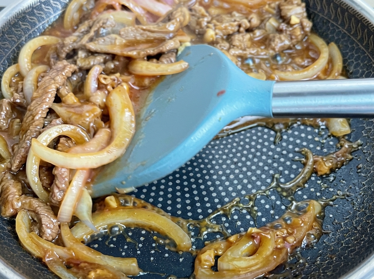 Manzo e cipolle mescolati in una salsa scura e densa.