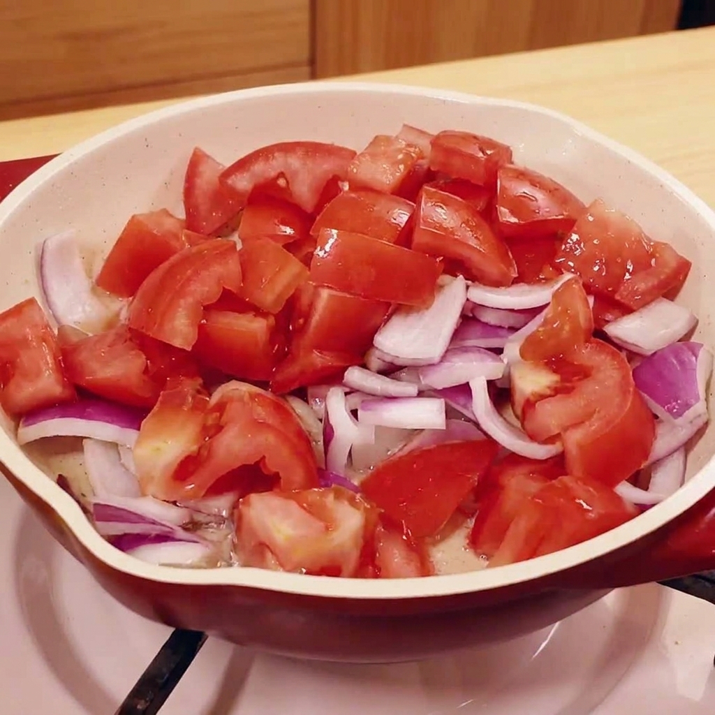 Pomodori e cipolle rosse tritati che cuociono in una padella.
