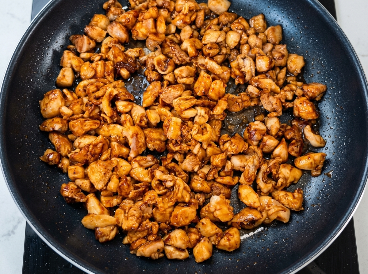 Cipollotti tritati versati nella padella con il pollo dorato.