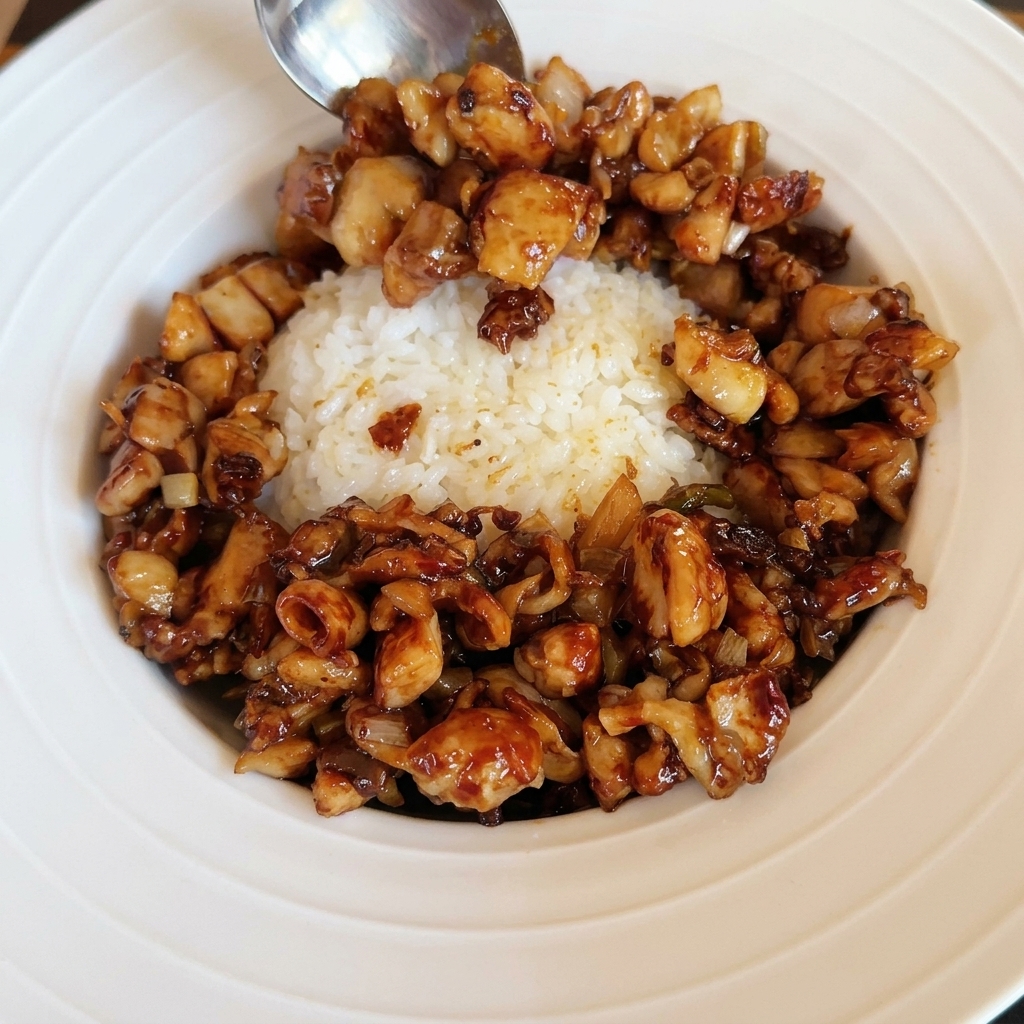 Un uovo allocchio di bue perfettamente fritto posizionato sopra una ciotola di riso e pollo saltato.