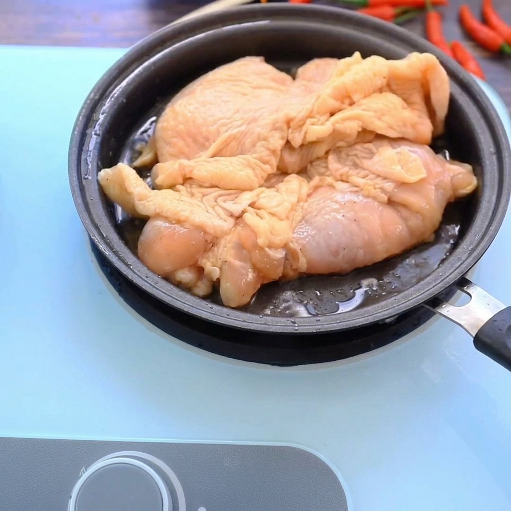 Cosce di pollo che rosolano in una padella calda, mostrando una superficie dorata e croccante.