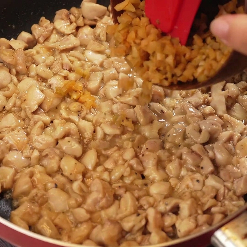 Verdure senapate finemente tritate e parti bianche di cipollotto aggiunte alla padella con i pezzi di pollo cotto dorato.