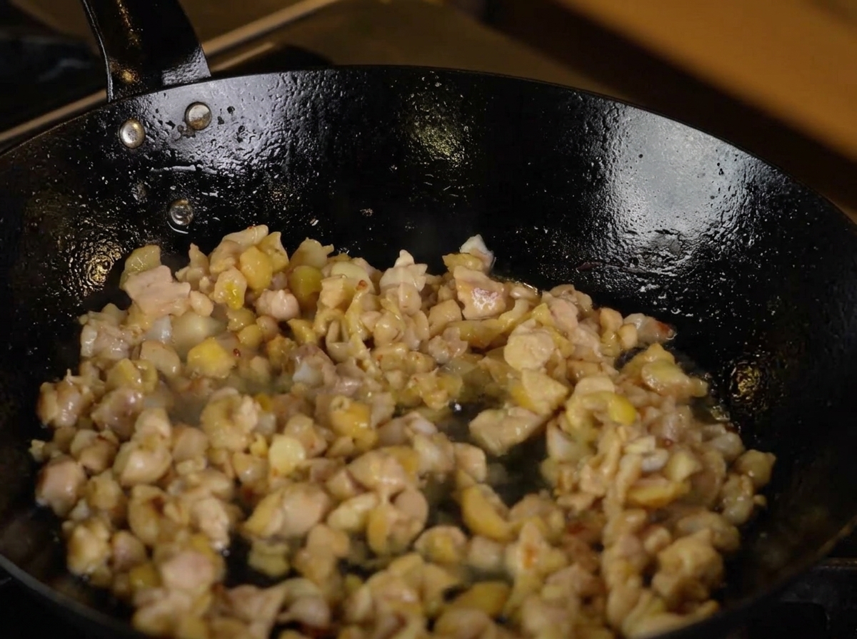 Sake versato in una padella contenente il pollo e gli aromi.