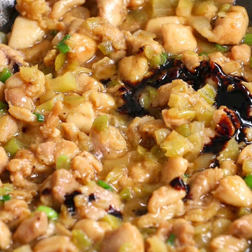 Salsa di soia scura versata in una padella con il pollo e le verdure.