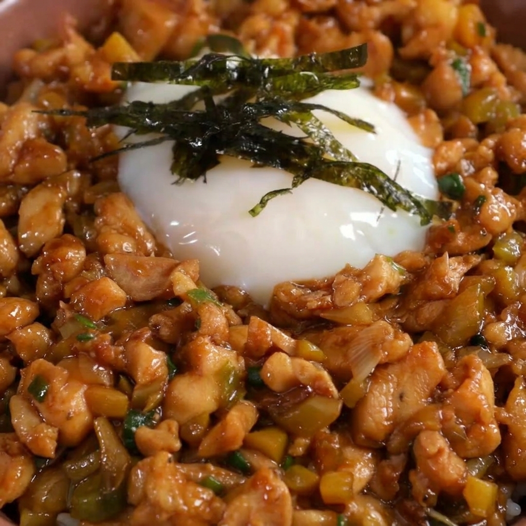 Alga nori tagliata sottile posizionata sopra luovo onsen in una ciotola di pollo e riso.