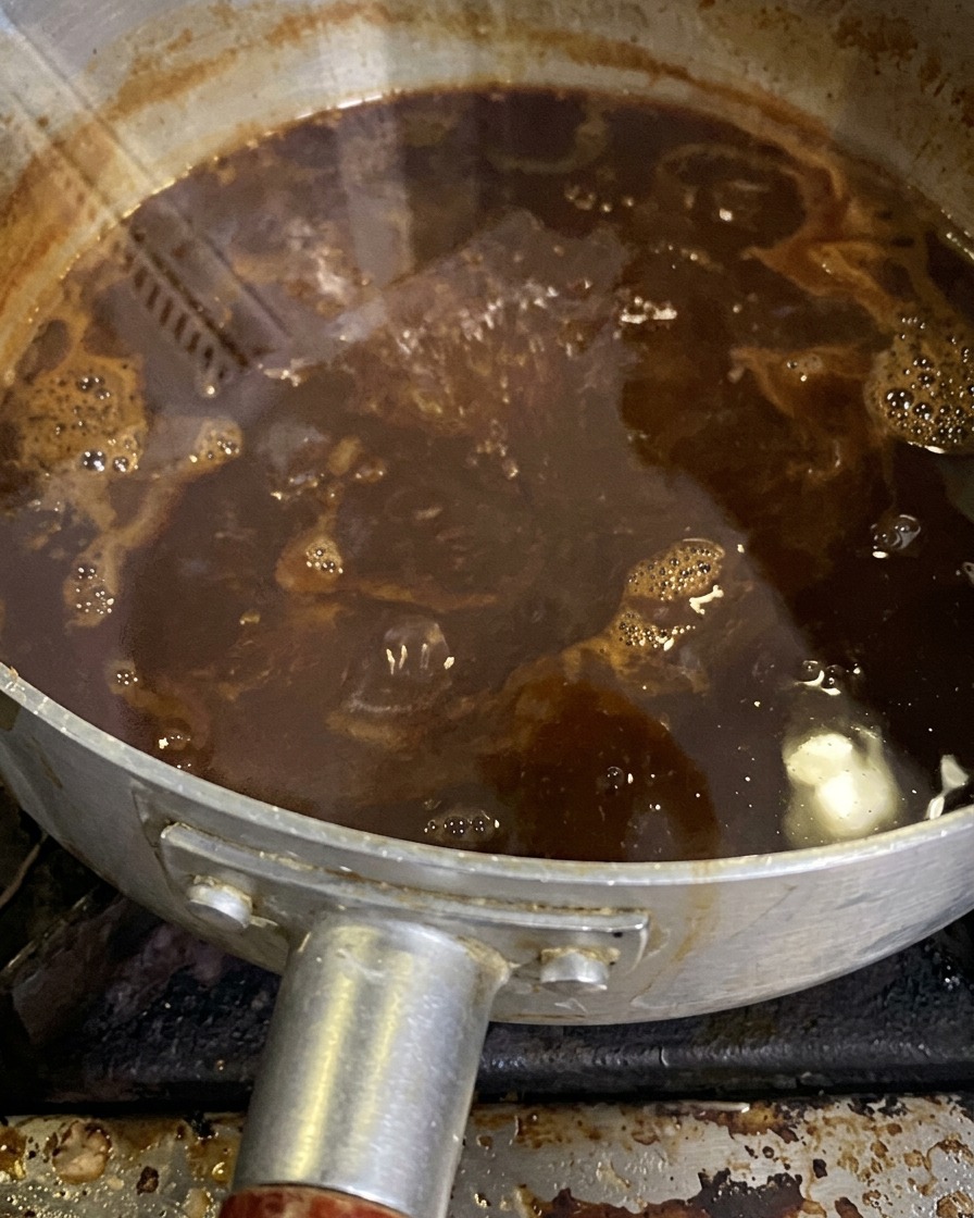 La salsa al miso che bolle dolcemente in un pentolino mentre si restringe.