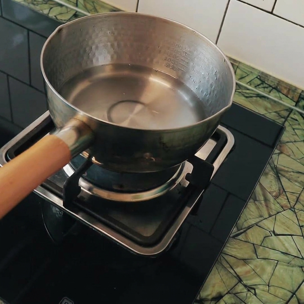 Cubetti di tofu aggiunti in una pentola di acqua bollente.