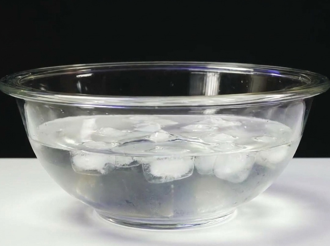 Un blocco di tonno immerso in una ciotola di vetro con acqua ghiacciata.
