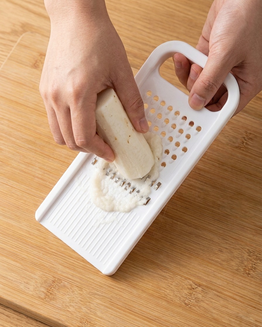 Pasta bianca di igname cinese appena grattugiata raccolta da una grattugia di plastica.