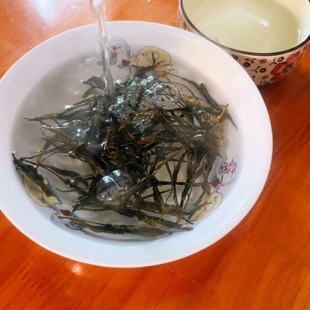 Acqua bollente versata su foglie di tè verde secche in una piccola ciotola decorativa.