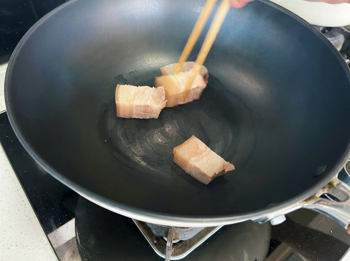 Cubetti di maiale rosolati in un wok fino a diventare di un colore dorato.