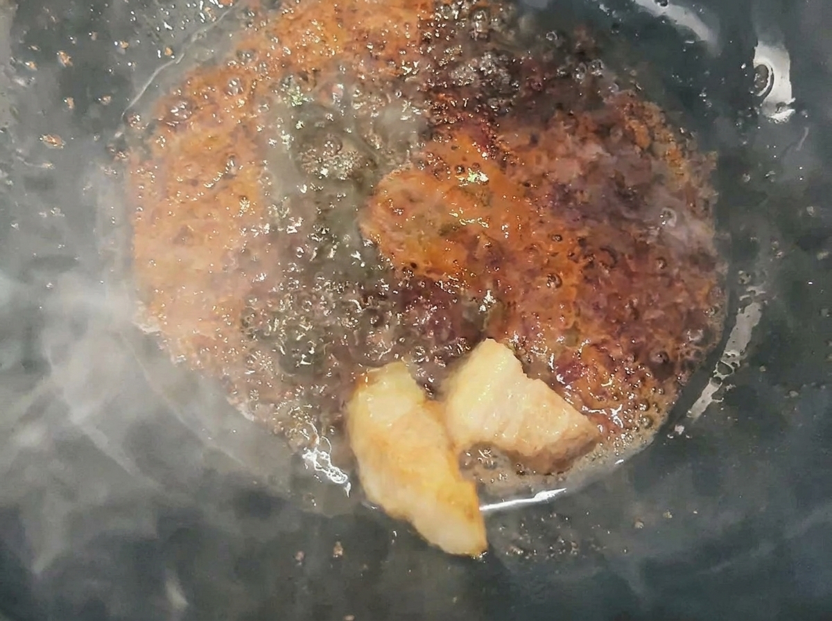 Cubetti di maiale saltati e ricoperti di caramello liquido in un wok.