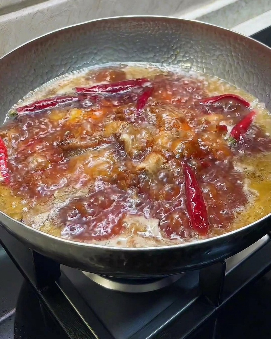 Salsa di soia scura e aceto aggiunti a una pentola di costine in cottura.