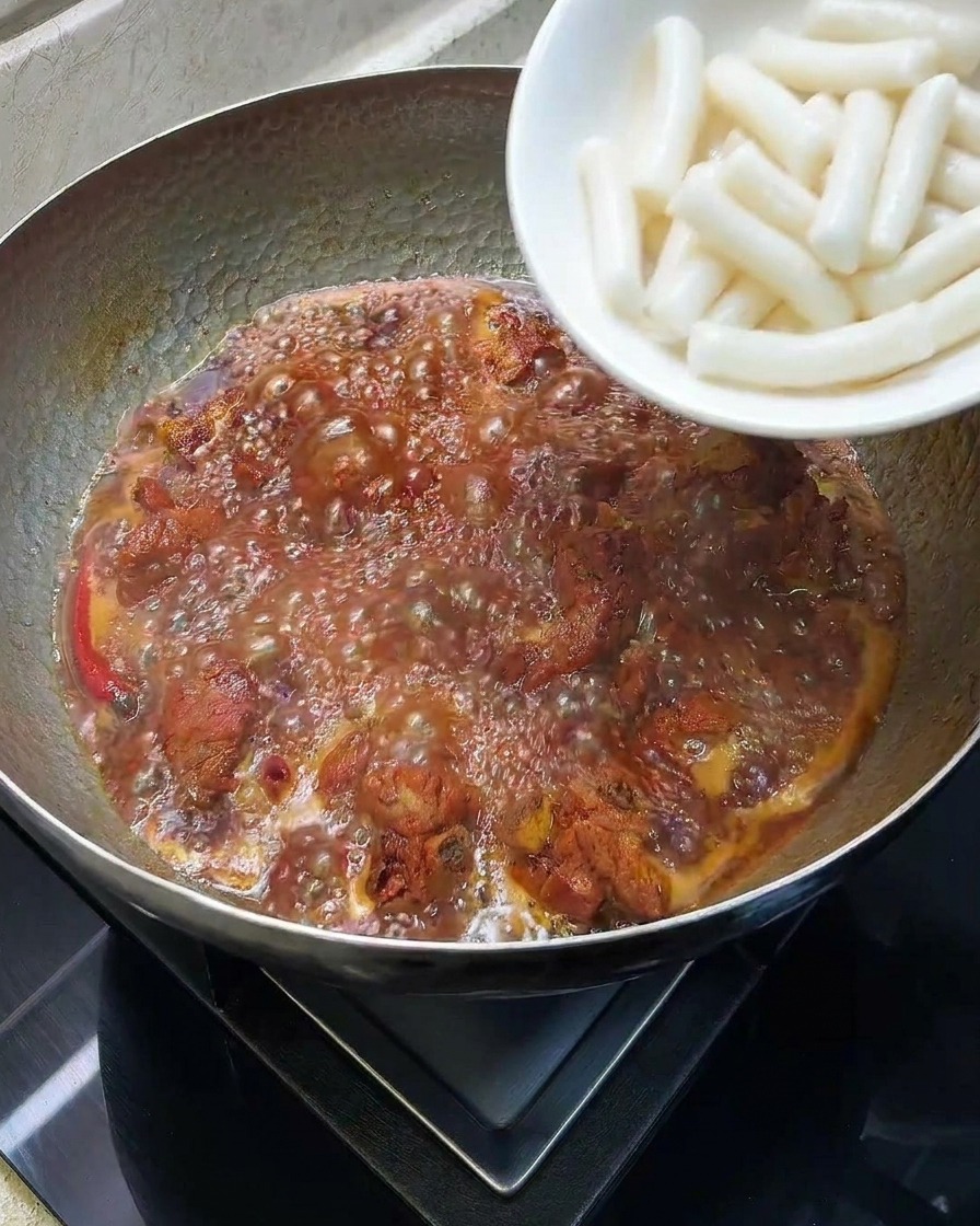 Gnocchi di riso cilindrici aggiunti in una pentola con le costine brasate.