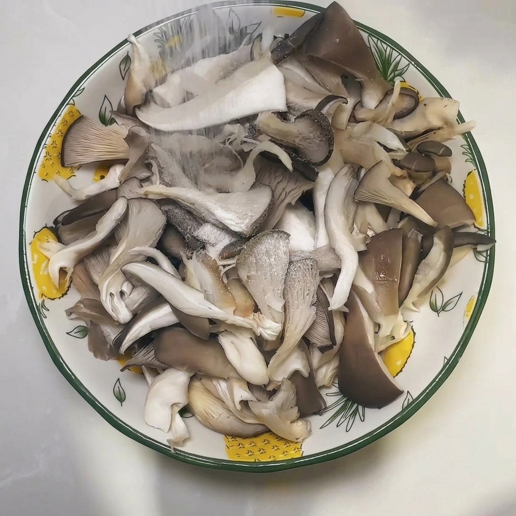 Una ciotola piena di funghi ostrica crudi strappati cosparsi di sale.