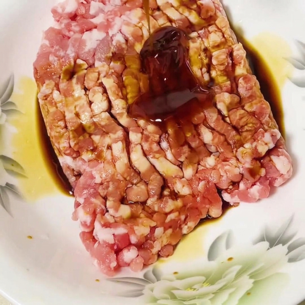 Salsa di ostriche aggiunta al maiale macinato condito in una ciotola.
