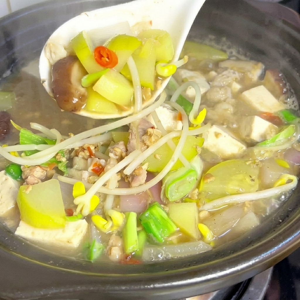 Spicchi di zucchina e fette di funghi shiitake versati in una pentola di brodo bollente.