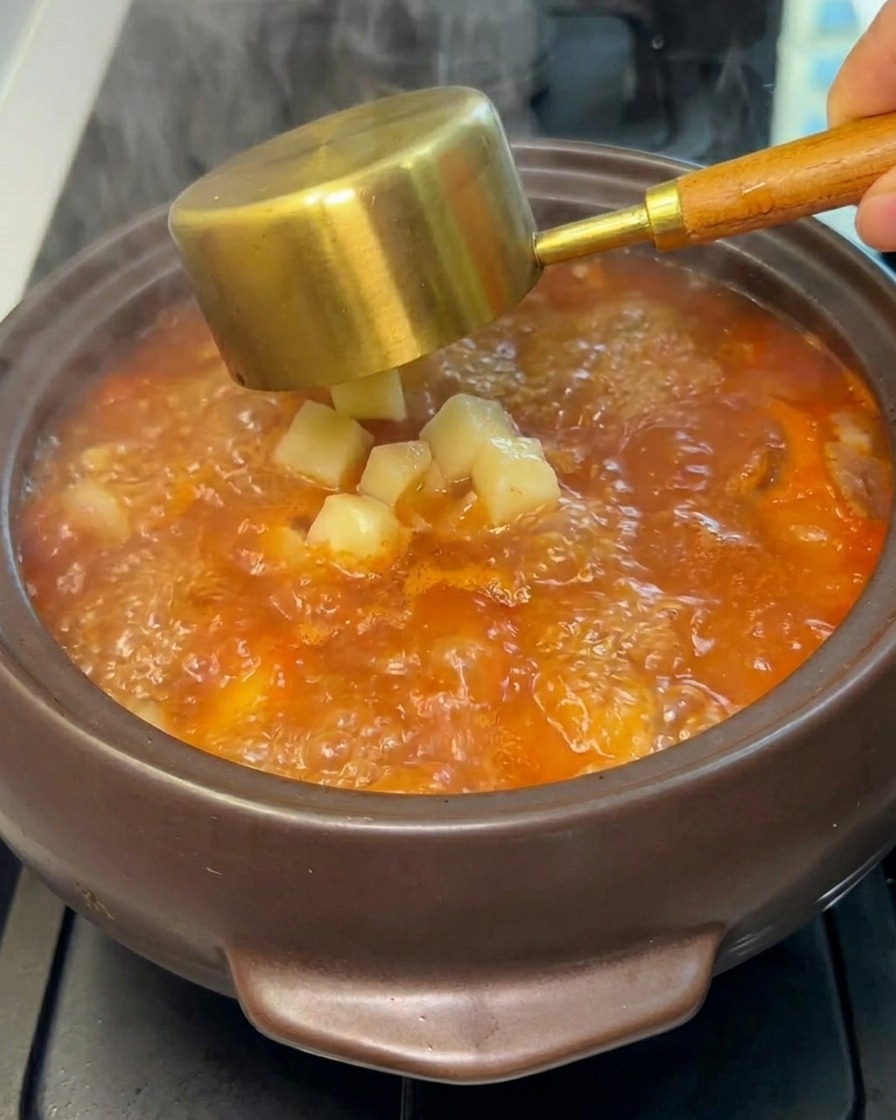 Patate crude a cubetti versate nello stufato in ebollizione.