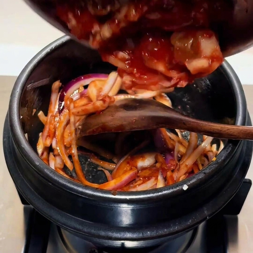 Kimchi tritato aggiunto nella pentola con la base di cipolla e salsa.