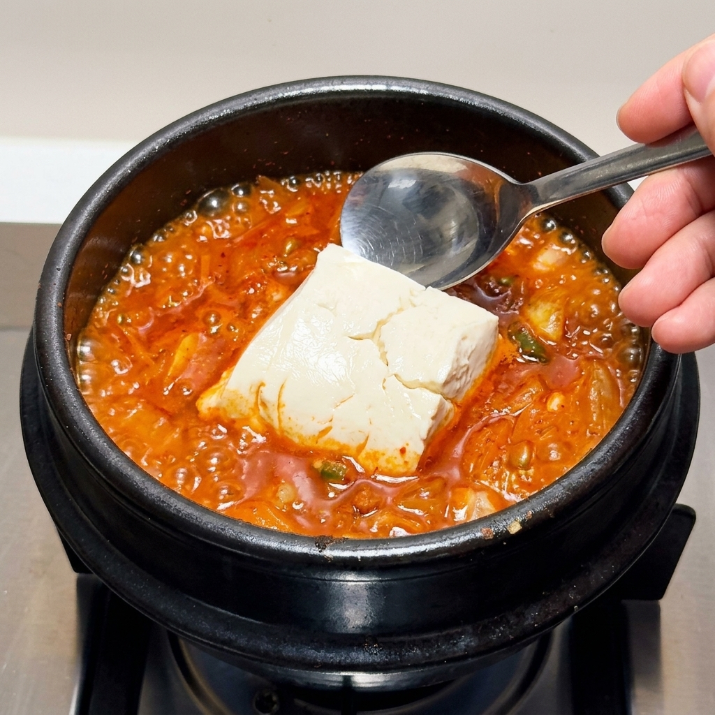 Grandi pezzi di tofu morbido inseriti delicatamente nello stufato bollente.