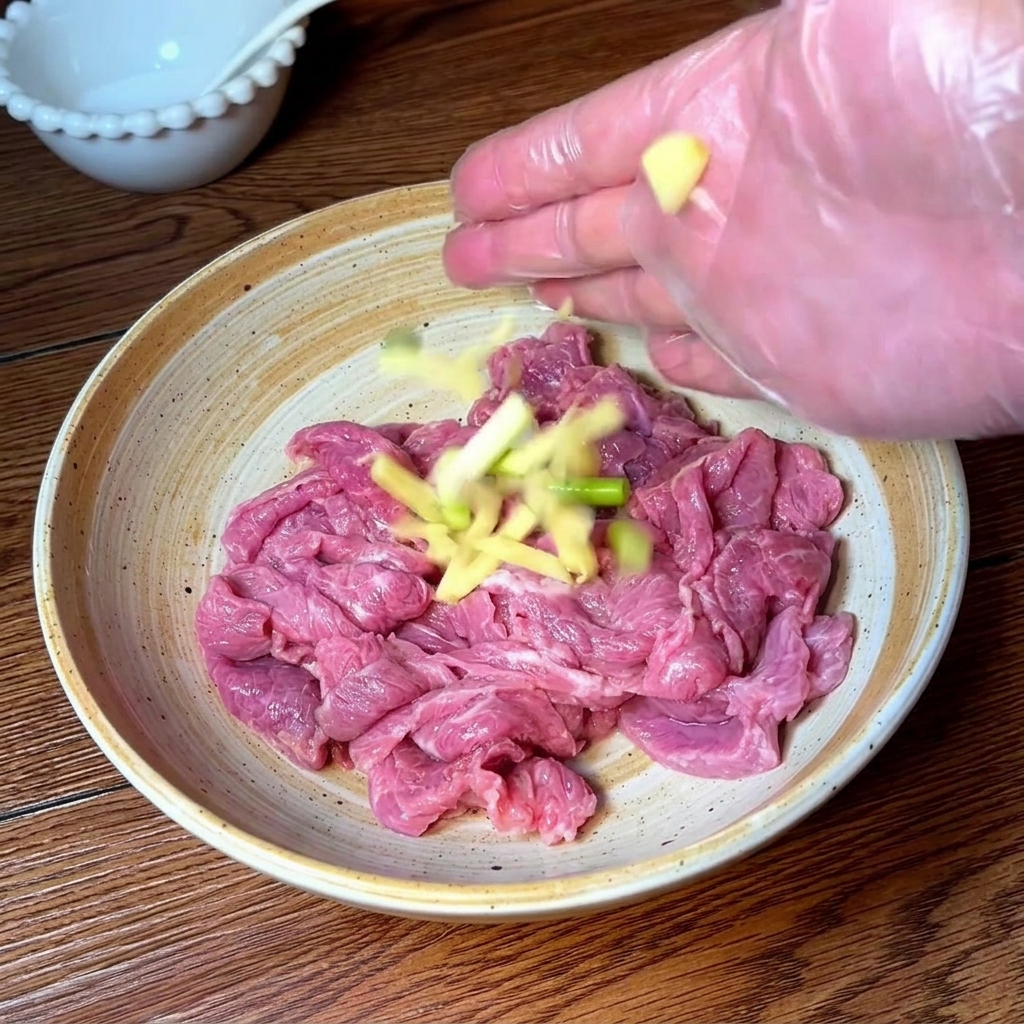 Mano con guanto che condisce e massaggia le fettine di manzo con aromi e spezie.