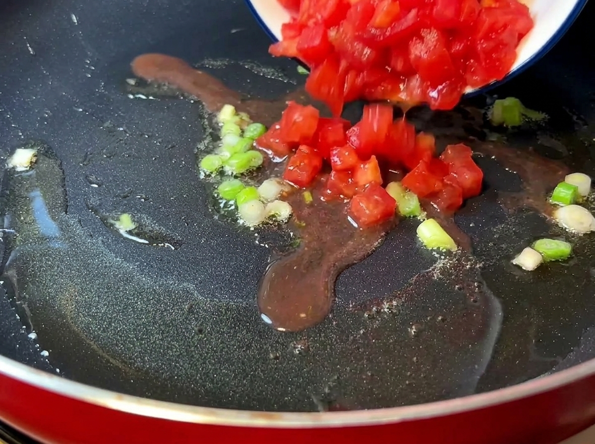 Pomodori a pezzi che cuociono in padella finché non diventano morbidi e succosi.