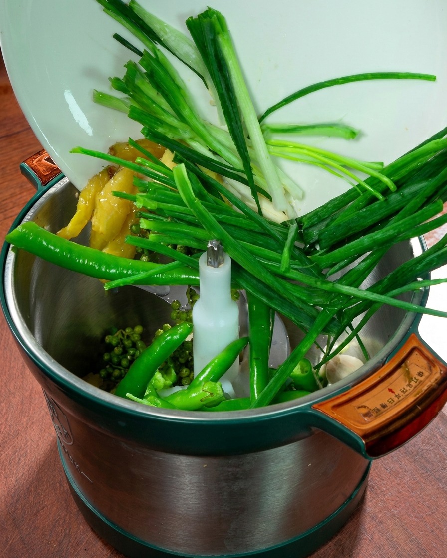 Un mixer contenente cipollotti, zenzero, aglio, peperoncini verdi freschi e pepe del Sichuan.