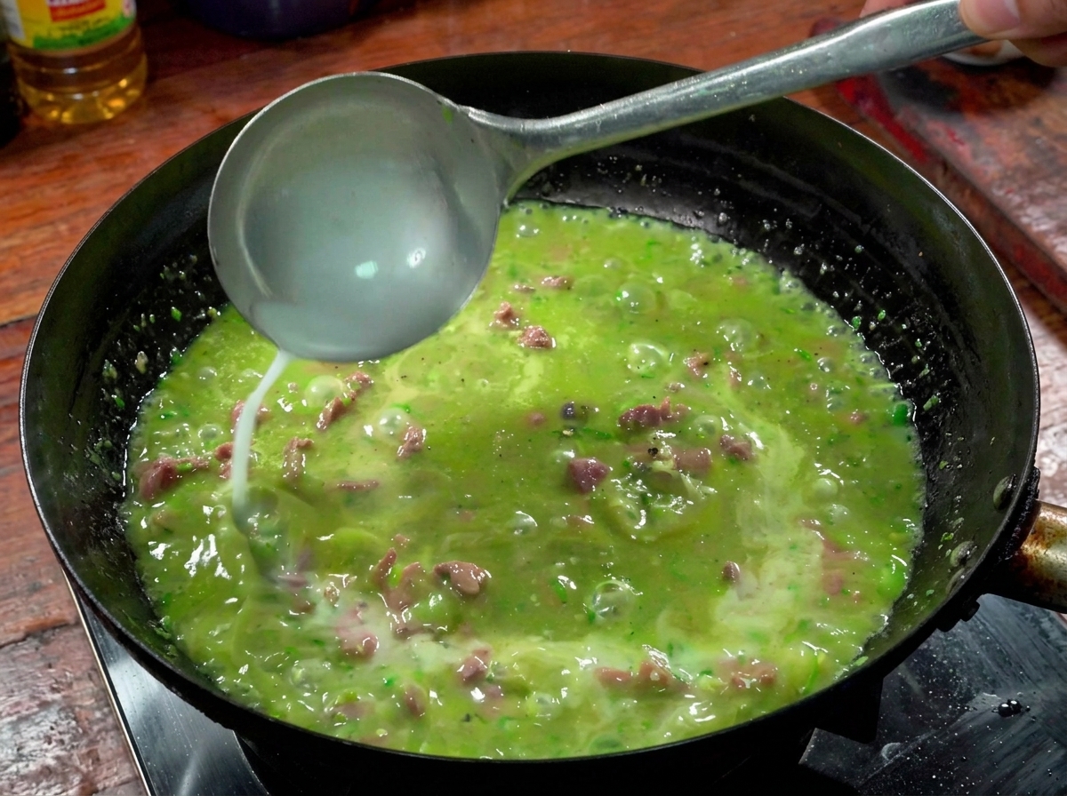 Un mestolo che versa acqua e amido nel brodo piccante del wok.